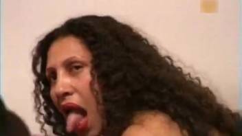 Wavy-haired dark-haired woman strokes and blows a canine's penis